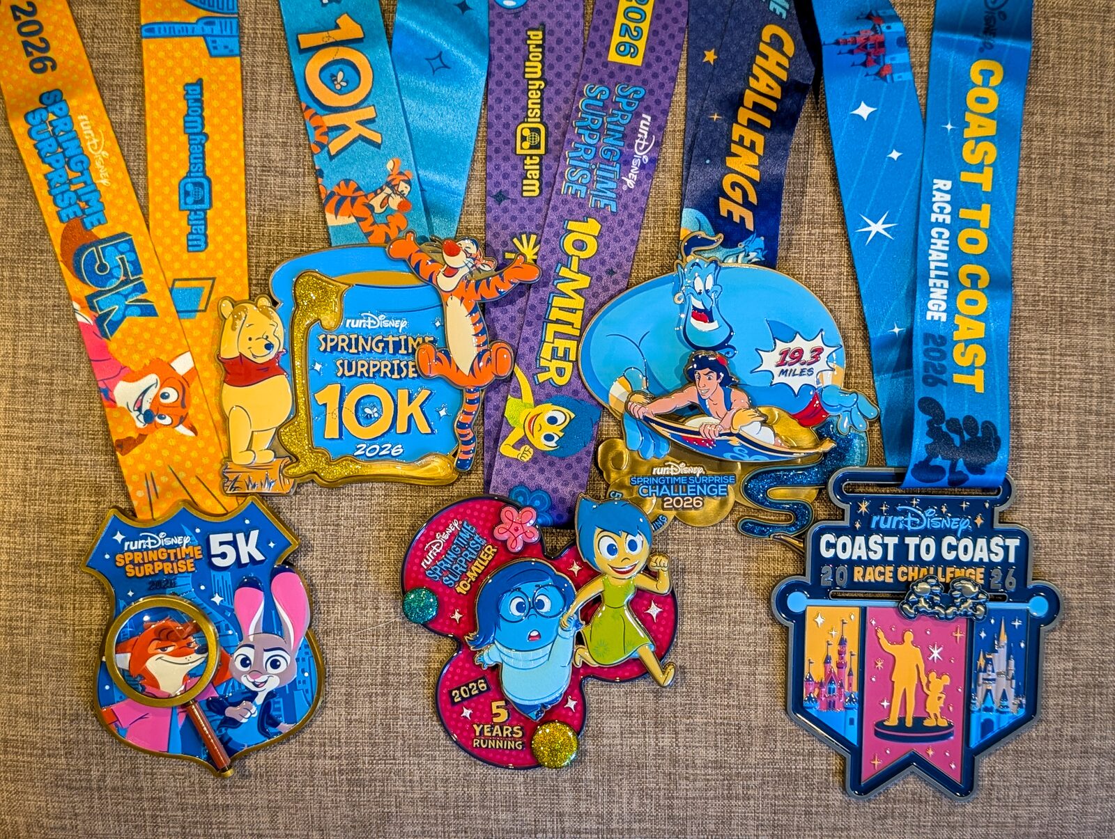 All five medals laid out - 5K, 10K, 10-Miler, Springtime Surprise Challenge, Coast to Coast