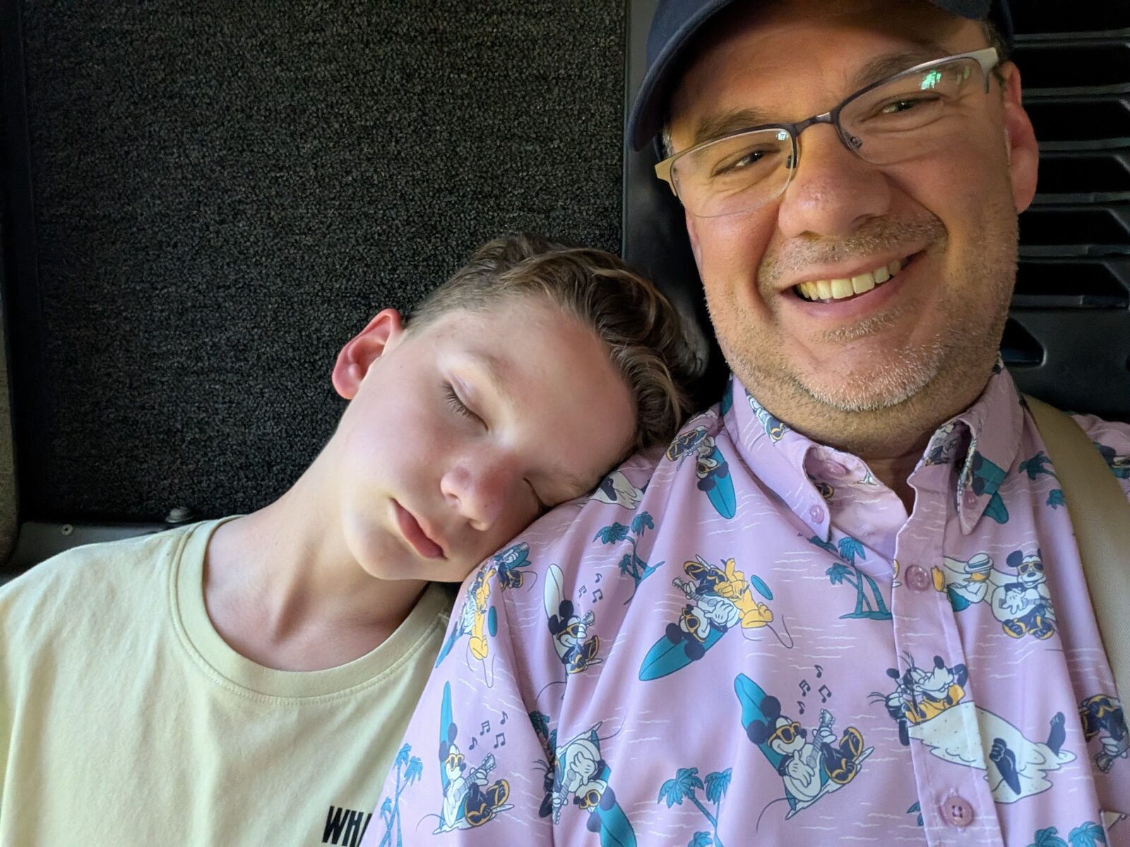Andrew asleep on his dad's shoulder on a Disney transport bus